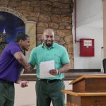 Two PEP students reading work at event inside prison